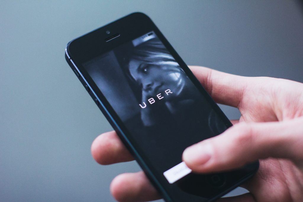 teléfono en mano con 'Uber' escrito en pantalla: conviértase en conductor para ganar dinero rápido hoy